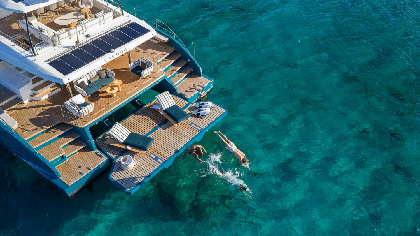 Lagoon EIGHTY 2 swim platform extended over clear turquoise water, with people diving into the sea