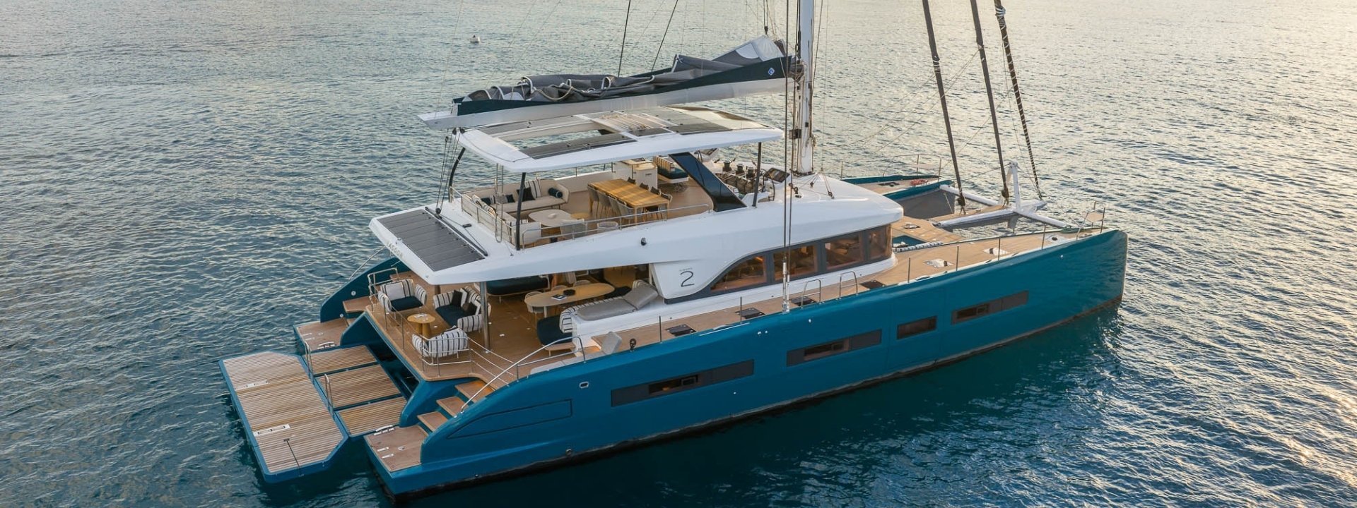 Lagoon EIGHTY 2 catamaran at anchor with crew on the flybridge in a sheltered bay